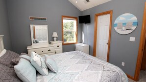 Une chambre à coucher comprenant un lit, une commode, une coiffeuse et un téléviseur.