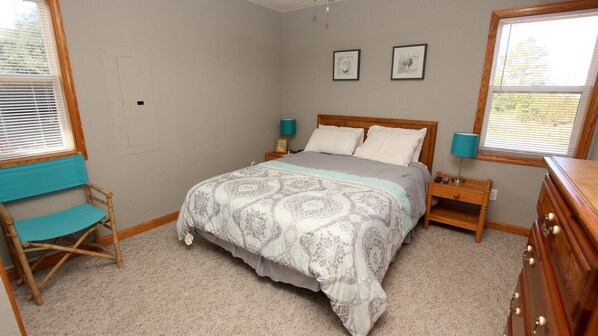 A bedroom with a bed, two bedside tables, a chair, and a dresser.