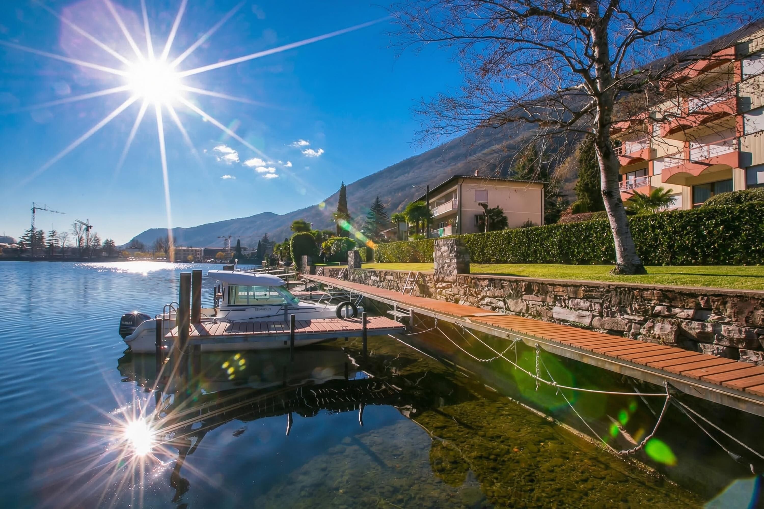 A boat docked at a marina with a clear sky and mountains in the background.