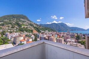 Ein Balkon mit Blick auf eine Stadtlandschaft, die Gebäude, einen Berg und ein Gewässer zeigt.