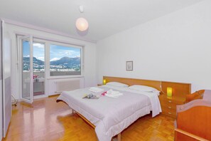 A bedroom with a bed, bedside tables, a window with a view, and a wooden floor. - Casa Taddei (Lugano)
