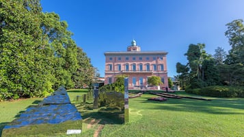 A large building with a central dome and symmetrical windows, surrounded by well-maintained grass and trees.