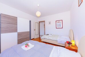 A bedroom with a bed, a bedside table with a lamp, a nightstand, a wardrobe, and a door leading to another room. - Casa Taddei (Lugano)