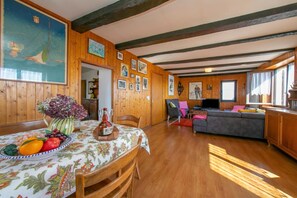 A wooden interior with a dining table set, a sofa, and a television.