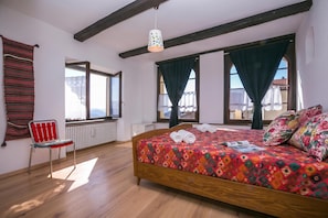 Ein Schlafzimmer mit einem hölzernen Bett, einem rot-weiß gestreiften Sessel und einem Fenster mit Blick auf Gebäude.