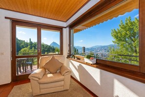 Un balcon avec un canapé, une vue sur la verdure et les montagnes, et un plafond en bois.