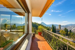 Un balcon offrant une vue sur le paysage urbain, une plante en pot et un coin salon agrémenté de coussins.