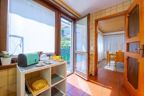 A kitchen with a toaster, a basket, and a window with a view of a balcony.