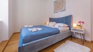 A bedroom with a bed, bedside table, lamp, and a wall decoration. - Heart of Lugano (Lugano)