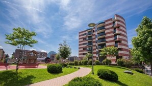 Un bâtiment moderne à la façade incurvée, entouré d’un espace vert bien entretenu et bordé d’un chemin pavé.