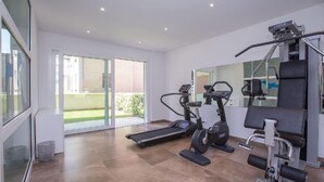 Une salle de sport moderne, équipée d’un tapis de course, d’un vélo elliptique et d’une machine de musculation.