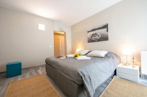A bedroom with a bed, bedside table, lamp, and artwork on the wall.