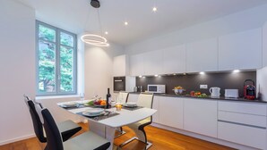 A modern kitchen with white cabinets, a dining table with chairs, and a large window. - Love of Lugano (Lugano)