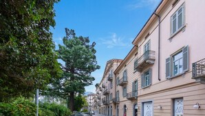 A street with parked cars, a building with balconies, and greenery. - Love of Lugano (Lugano)