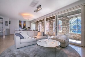 Una sala de estar moderna con un sofá blanco, una mesa redonda de centro y una cocina al fondo.