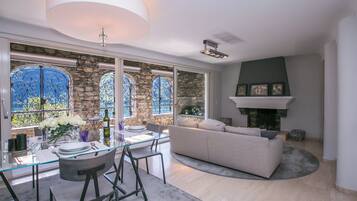 Una sala moderna con una mesa de comedor de vidrio, paredes de piedra y una chimenea.