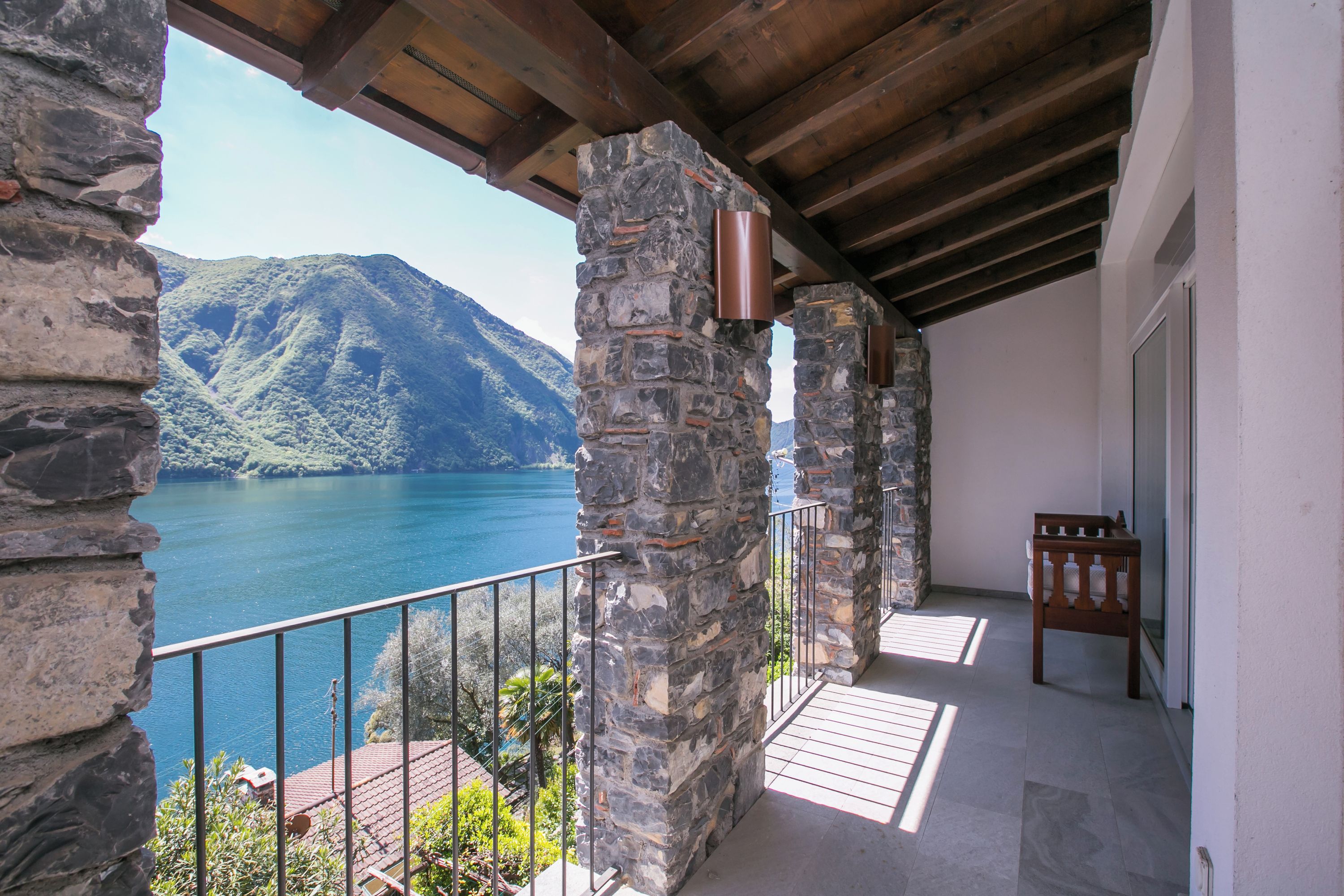 A stone balcony with a view of a lake and mountains.