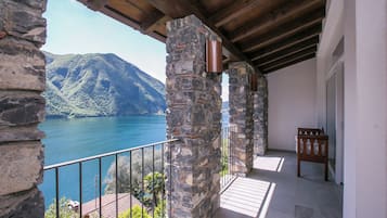 Ein aus Stein gestalteter Balkon mit Blick auf einen See und Berge.