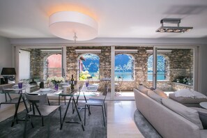 Un interior moderno con comedor, sofá y ventanas amplias con paredes de piedra.