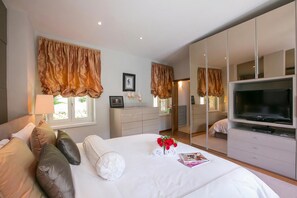 A hotel room with a bed, a TV, a dresser, a mirror, and a window with curtains. - Magic Gandria (Lugano)