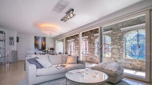 A modern living room with a white sofa, a round coffee table, and a kitchen in the background. - Magic Gandria (Lugano)