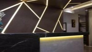A modern reception area with a geometric light design on the wall and a marble counter. - Hotel Meriton (Mumbai)