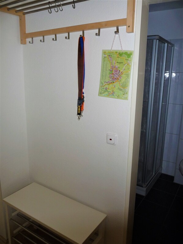 A room with a wooden coat rack, a map on the wall, a white switch, and a bench. - Apartment foresight (Steibis)