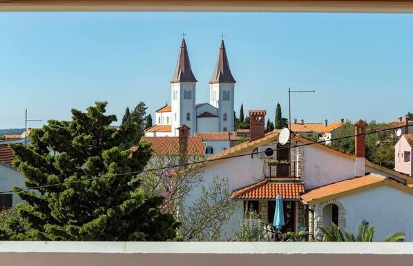 En vy över en kyrka med två torn, omgiven av bostadshus med röda tegeltak.