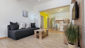 Una sala de estar moderna con un sofá gris, una pequeña mesa de centro de madera y una planta en maceta.