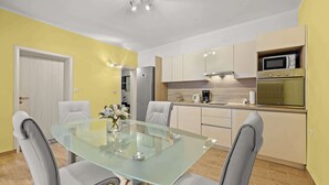Una cocina moderna con una mesa de comedor de vidrio, sillas grises y un microondas.