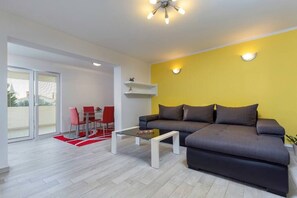 Un salon moderne avec un canapé, une table basse en verre et un coin repas avec des chaises rouges.