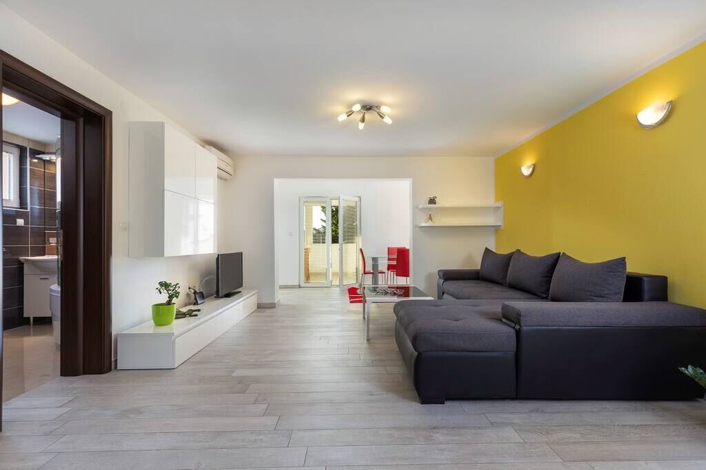 Uma sala de estar moderna com um sofá, TV e uma parede de destaque amarelo vibrante.