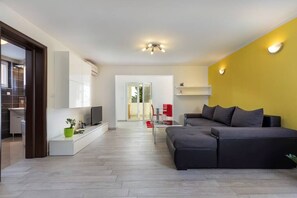 A modern living room with a sofa, TV, and a bright yellow accent wall.