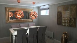 A dining area with a white table, grey chairs, and a large mirror above. - Notodden Sentrum Apartment NO 3 (Notodden)