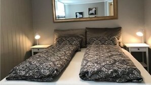 A twin bed with patterned bedding, a mirror above, and bedside lamps. - Notodden Sentrum Apartment NO 3 (Notodden)