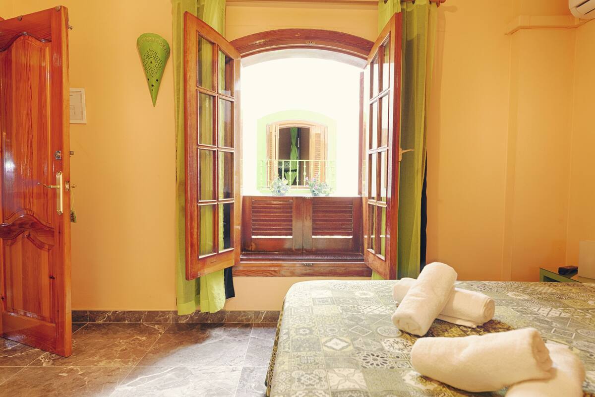 Une chambre d’hôtel avec un lit, une fenêtre donnant sur un paysage agréable et une porte.