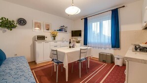 A compact hotel room with a dining area, kitchenette, and a bed.