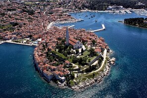 Luftaufnahme einer Küstenstadt mit einer markanten Kirche auf einer von einer Festung umgebenen Insel.
