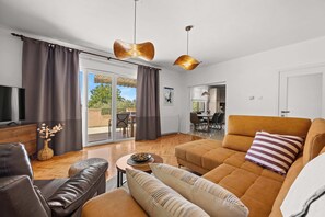 A modern living room with a sofa, a coffee table, and a television. - Holiday Home with pool and garden - Tervis (Trviž)