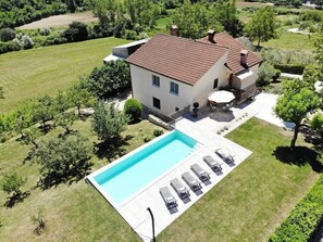 A two-story house with a swimming pool, a patio with lounge chairs, and a well-maintained lawn. - Holiday Home with pool and garden - Tervis (Trviž)