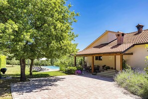 A house with a tiled roof, a covered patio, and a swimming pool. - Holiday Home with pool and garden - Tervis (Trviž)