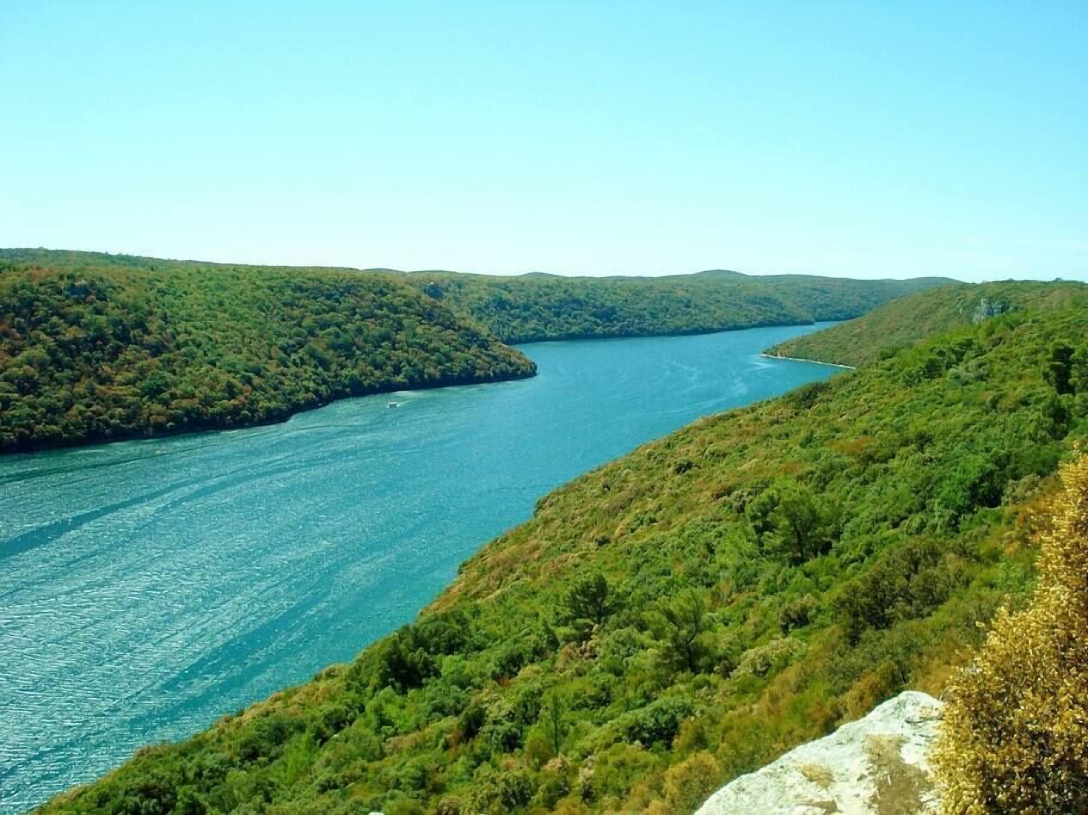 A river winding through a mountainous landscape with dense greenery on both sides.