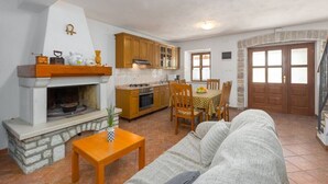 Una sala de estar con chimenea, un comedor con mesa y sillas, y una cocina con gabinetes de madera y estufa.