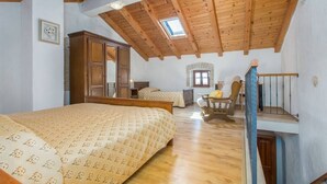 Un dormitorio con techo de madera, una cama, una silla y una escalera.