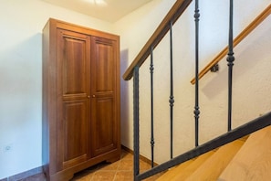 Eine Holztreppe mit schwarzer Geländer und einer Holztür links.