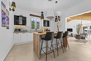 A modern kitchen with a central island, bar stools, pendant lighting, and a dining area with a wooden ceiling. - Five bedroom villa Emily with pool in Medulin (Medulin)