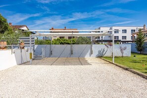 A covered outdoor area with a gravel floor, a white pergola, and a view of residential buildings in the background. - Five bedroom villa Emily with pool in Medulin (Medulin)
