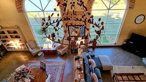 Amplia sala de estar con un gran ventanal, un candelabro, un sofá y un televisor.