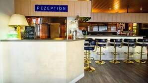 A reception area with a sign labeled "RECEPTION," a counter with a lamp, and a bar with stools.