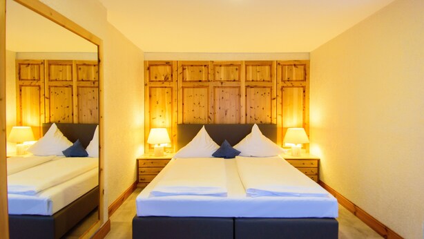 A double bed with a wooden headboard, two bedside tables with lamps, and a large mirror on one wall.